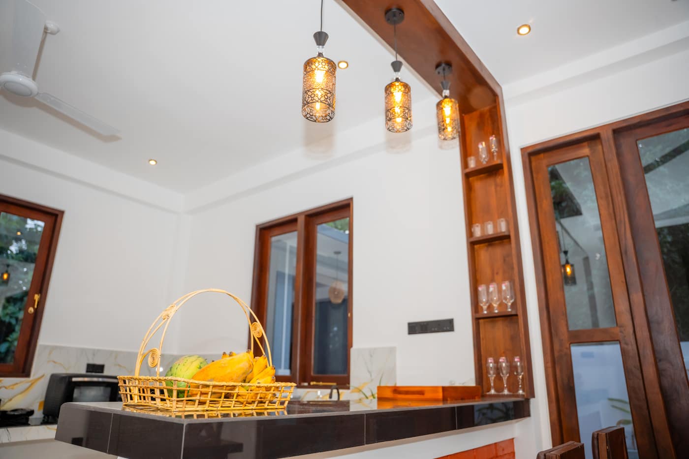 The breakfast counter under its pendant lights, a basket of fruit on the worktop