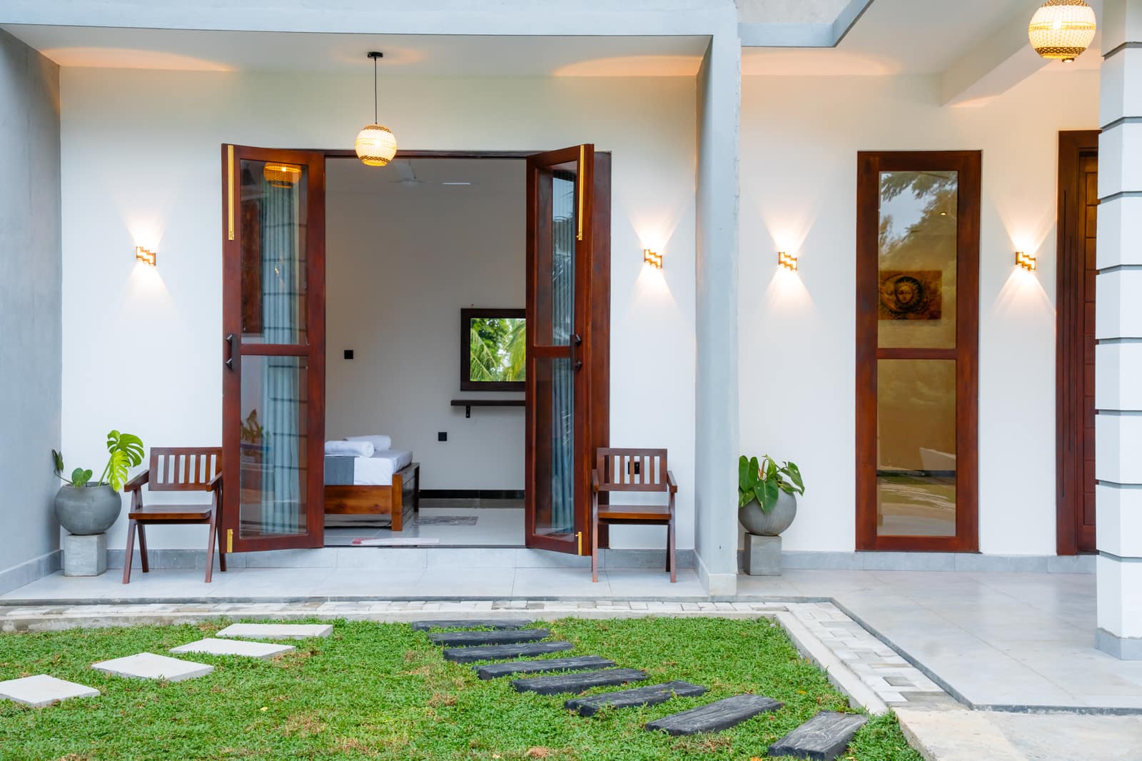 Stepping stones across the lawn to the terrace, with the room doors folded open and two chairs outside